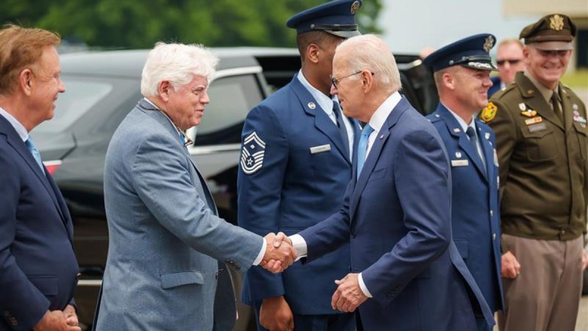 President Joe Biden shakes hands with Rep. John Larson, D-Conn., second from left, as he arrives at Bradley International Airport in Windsor Locks on Friday. Gov. Ned Lamont looks on at left.